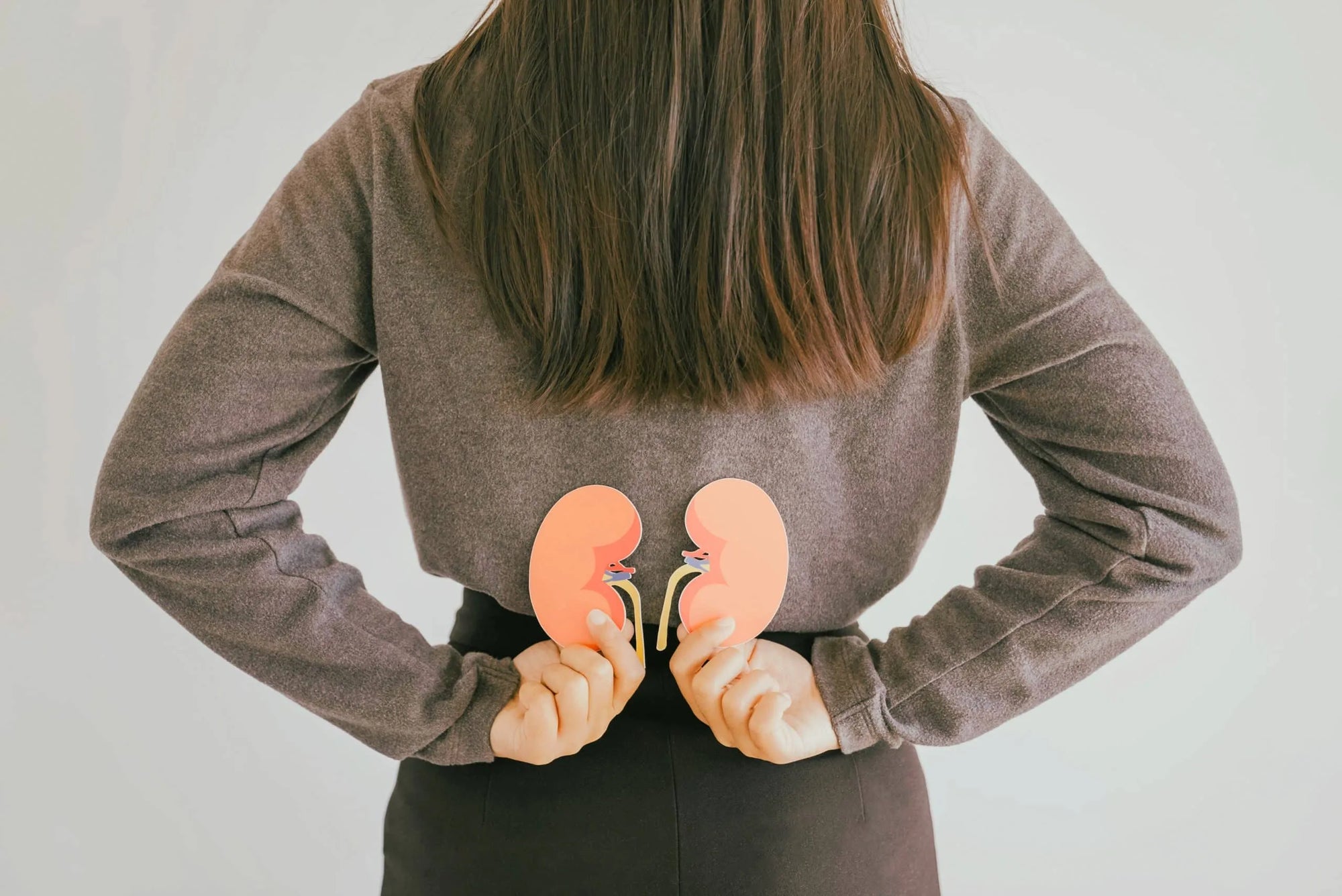 A woman holding adrenal gland shapes behind her back