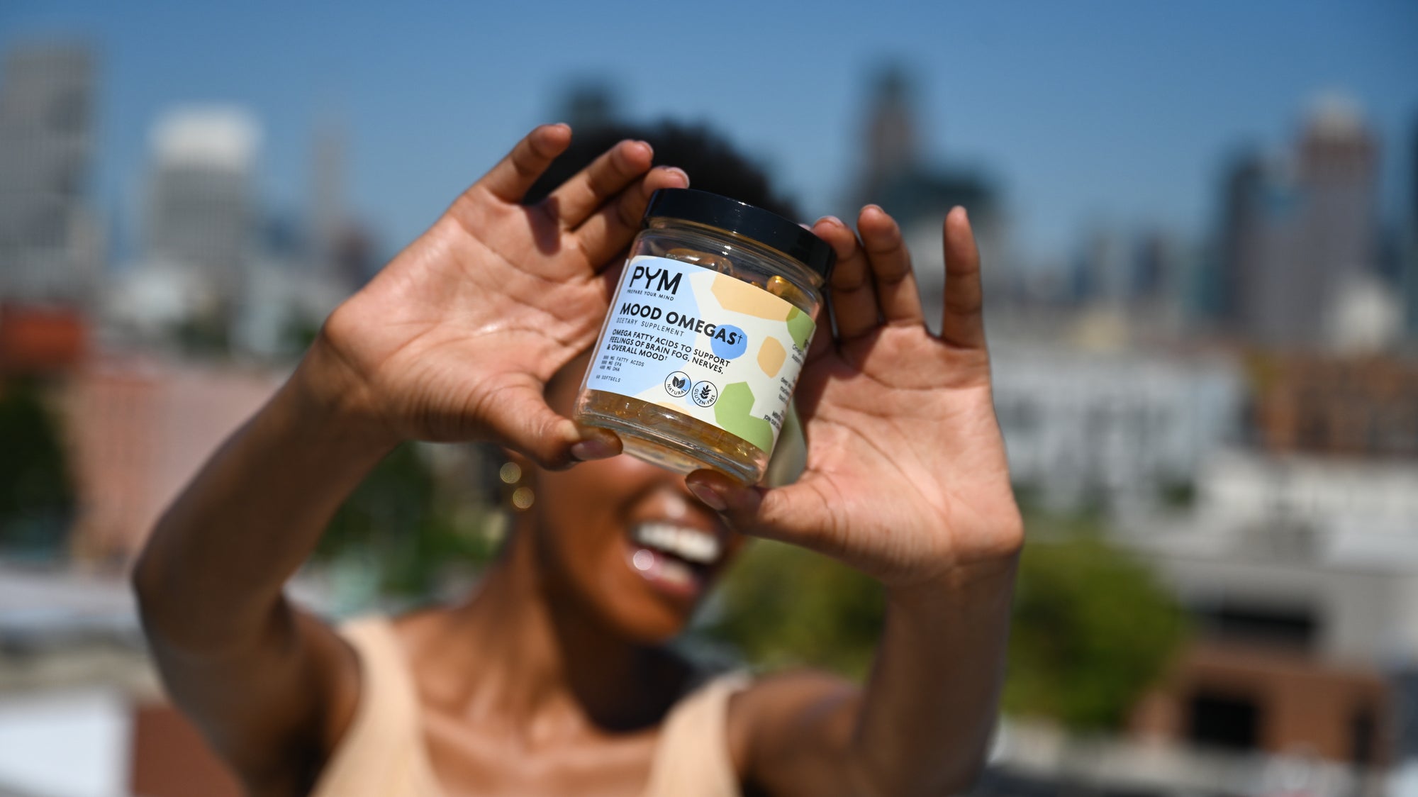 Person holding a jar labeled 'PYM MOOD OMEGA† Dietary Supplement Omega Fatty Acids to Support Feelings of Brain Fog, Nerves, & Overall Mood'