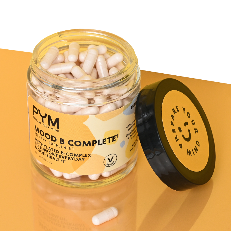 Jar of PYM Mood B Complete+ dietary supplement capsules. Label text: "PYM PREPARE YOUR MIND MOOD B COMPLETE+ DIETARY SUPPLEMENT METHYLATED B-COMPLEX TO SUPPORT EVERYDAY MOOD HEALTH 30 CAPSULES". Lid text: "PREPARE YOUR MIND" with a smiley face.