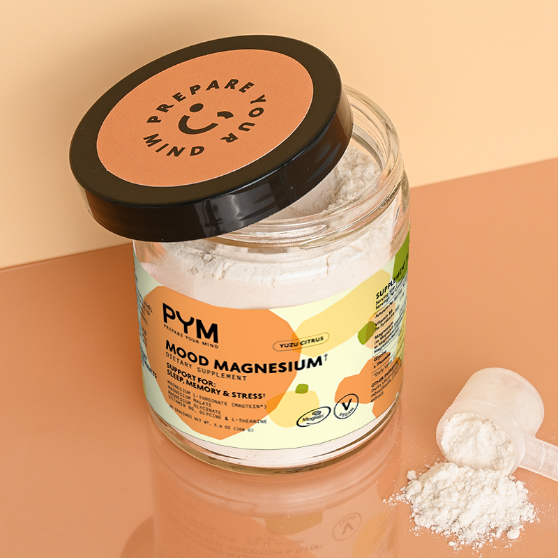 Jar of Mood Magnesium dietary supplement powder with label text including 'PYM Elevate Your Mind', 'Mood Magnesium', 'Dietary Supplement', 'Support for Sleep, Memory & Stress', and 'Yuzu Citrus'. Lid text reads 'Prepare Your Mind'. Powder and scoop beside jar.