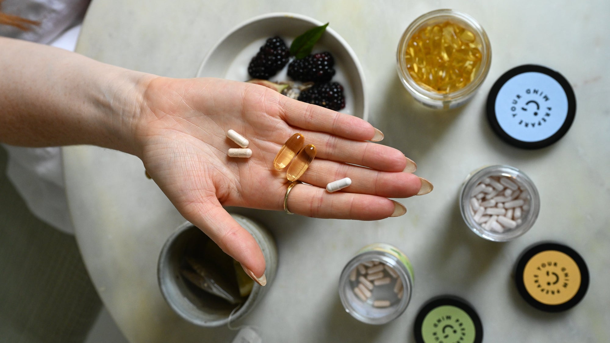 A hand holding several omega-3 supplements