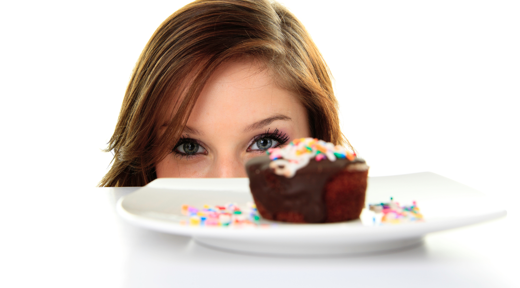 Woman looking tempted by a chocolate cupcake