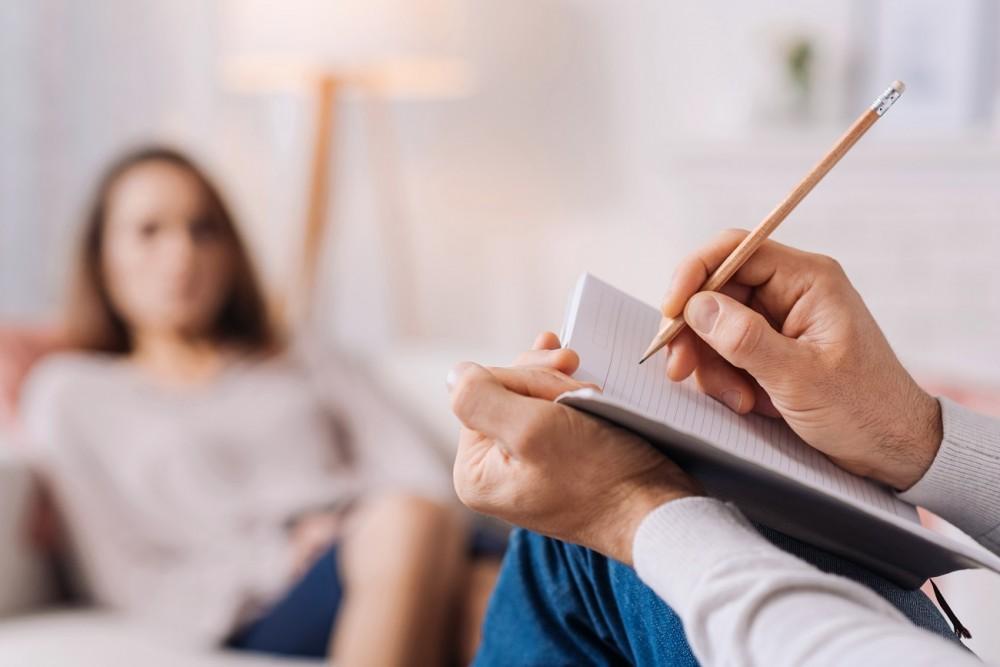 A therapist writes notes while talking about exposure therapy