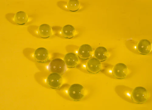 Clear glass marbles scattered on a yellow surface casting shadows