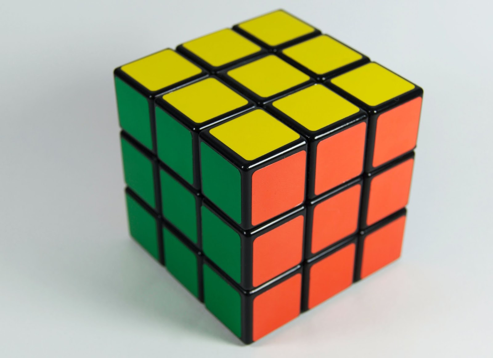 Solved Rubik's Cube showing green, yellow, and orange faces on a white background.