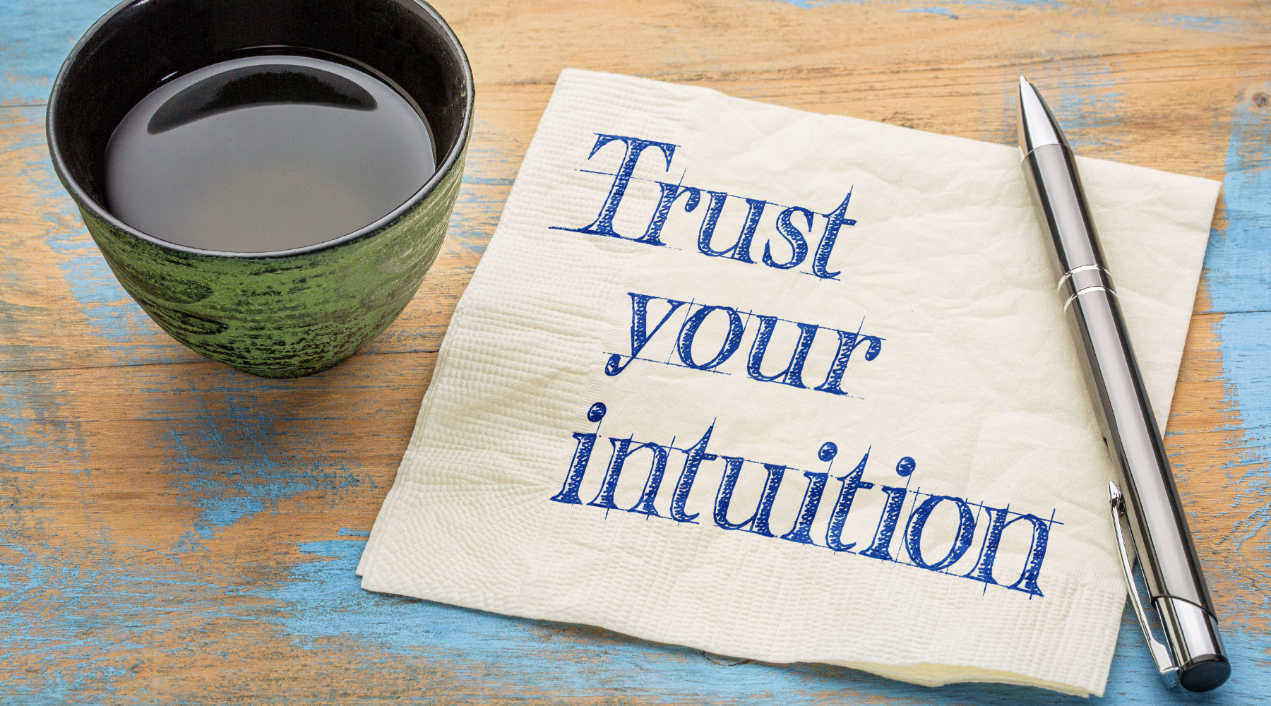 Cup of tea, pen, and napkin with the words 'Trust your intuition' written on it