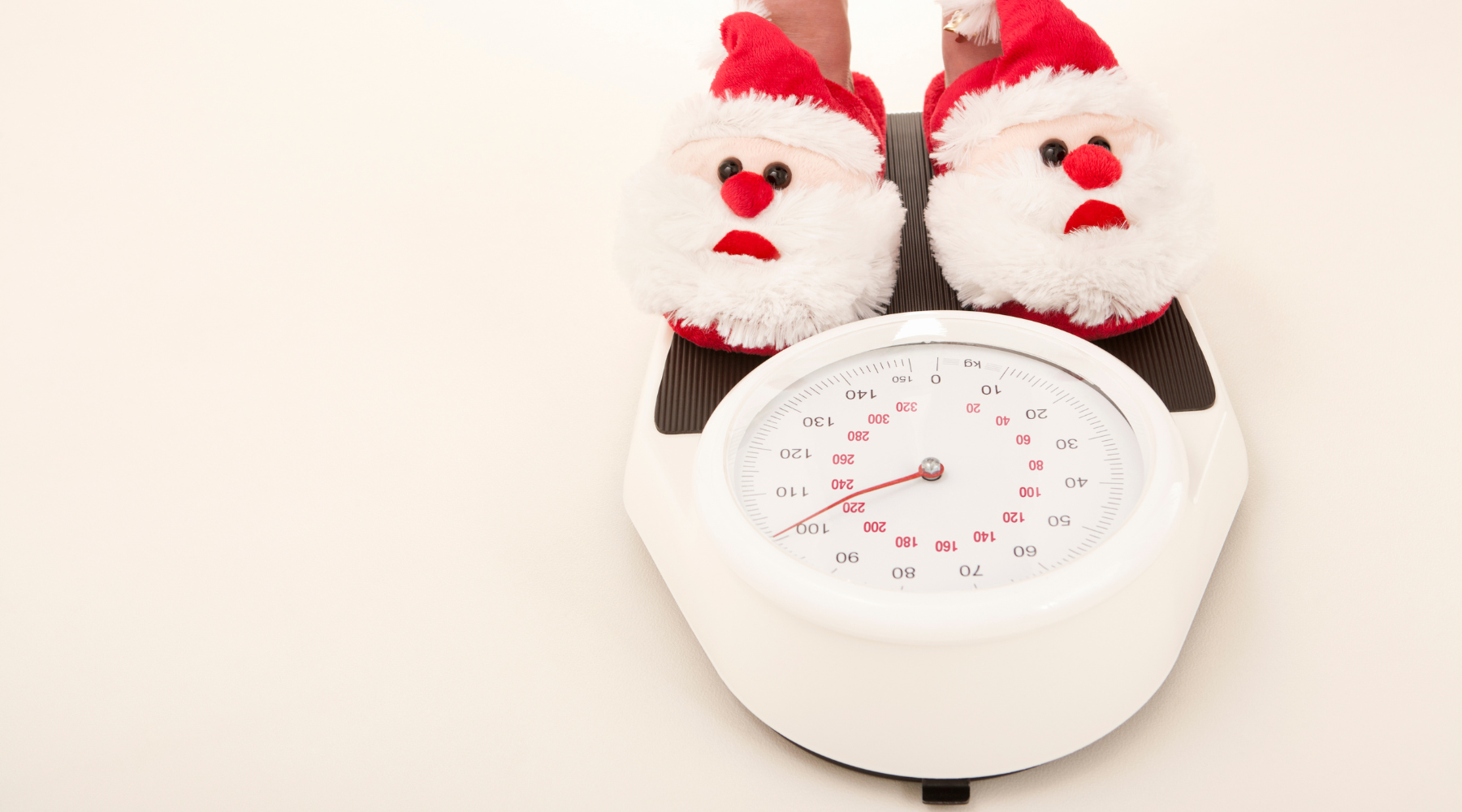 Standing on a scale showing weight gain with santa clause slippers. How to avoid weight gain in the winter months
