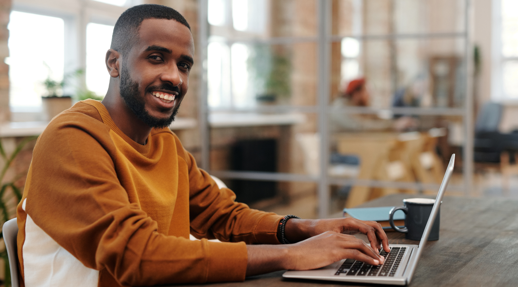 A man smiles while typing on the computer looking focused