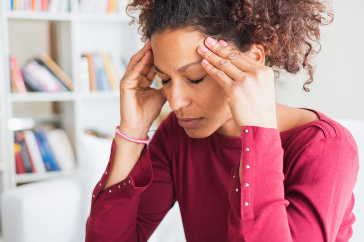 An African American woman rubbing her temples and looking stressed