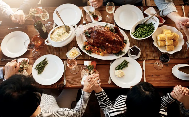 Family gathering for Thanksgiving dinner holding hands