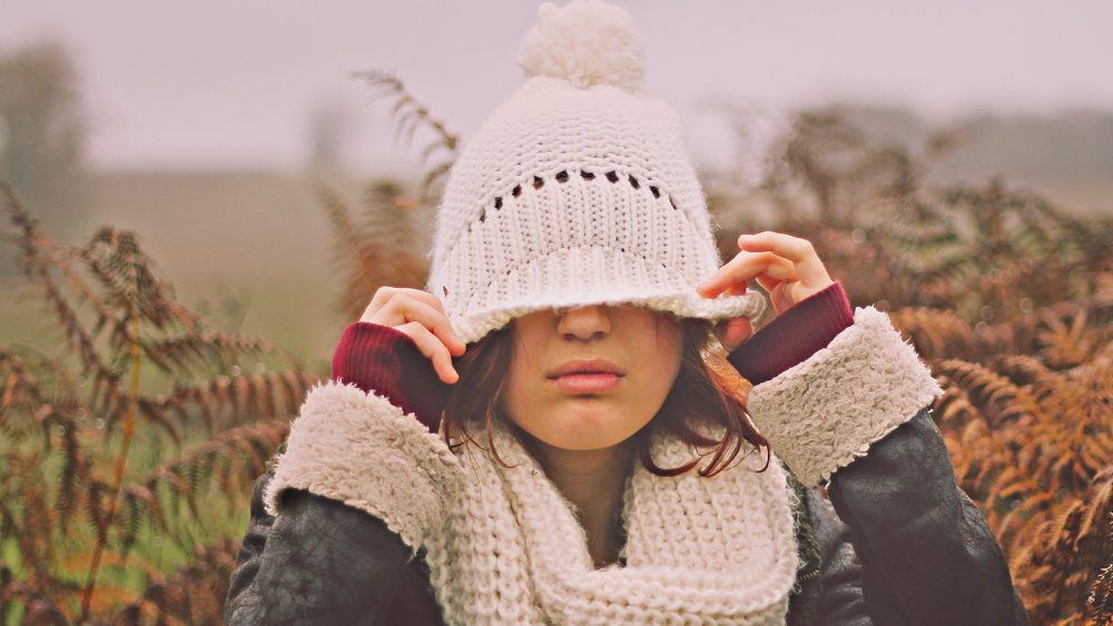 september scaries woman with hat covering eyes looking stressed in the fall