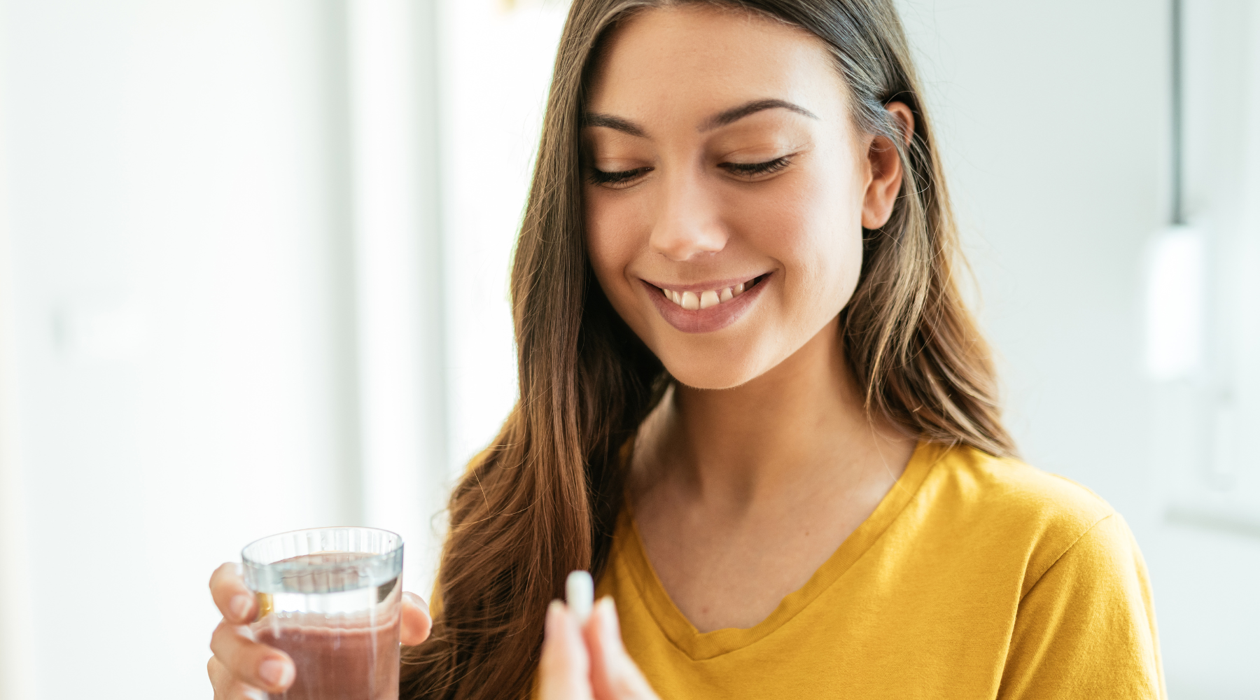 Woman smiling and taking a magnesium supplement to boost oxytocin levels