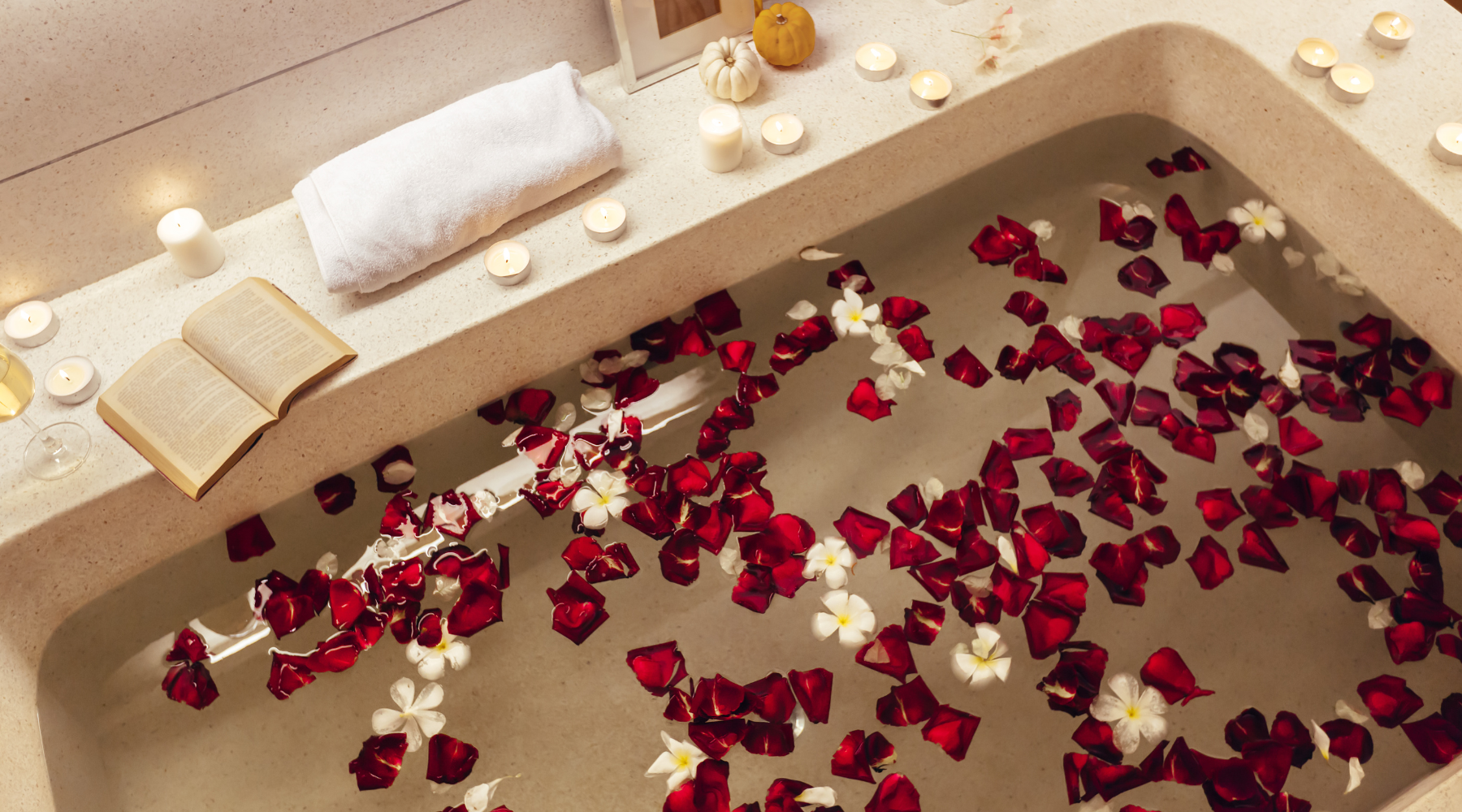 A relaxing bath with dim lighting, rose petals and a book for Valentine's Day