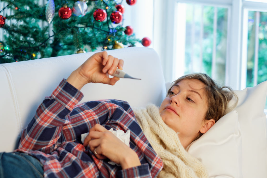Woman holding a thermometer with leisure sickness during the holidays